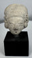Pre-Columbian ceramic effigy head with elongated skull shape and archaeological surface patina.