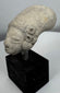 Pre-Columbian funerary terracotta head fragment with closed eyes and weathered archaeological surface.