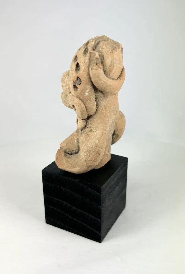 West Mexican terracotta funerary figurine showing a seated woman with pierced eyes and earspools