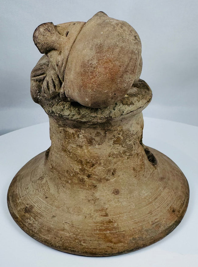 Ancient Ecuadorian ceremonial brazier lid featuring a recumbent figure, large ear ornaments, and vented construction.
