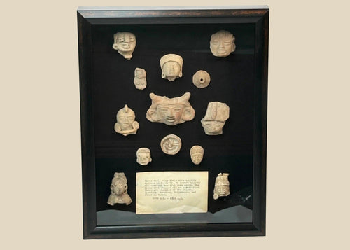 Shadowbox of 13 Pre-Columbian Mesoamerican terracotta fragments, including heads, maskettes, figurines, and spindle whorls from Teotihuacan and Veracruz traditions, 200 BCE–900 CE