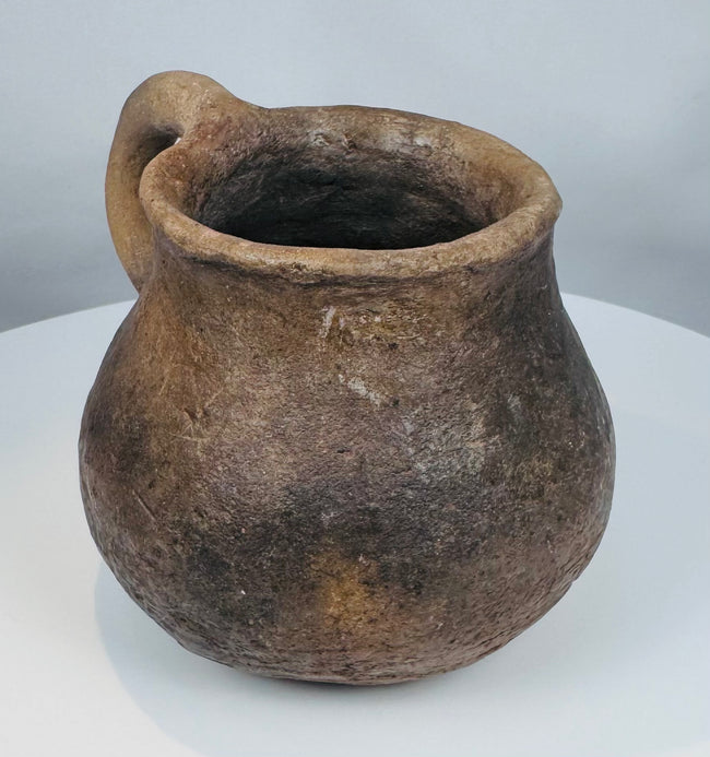 Archaeological Casas Grandes pottery mug with curved handle and weathered earthenware surface from the ancient Chihuahua region.