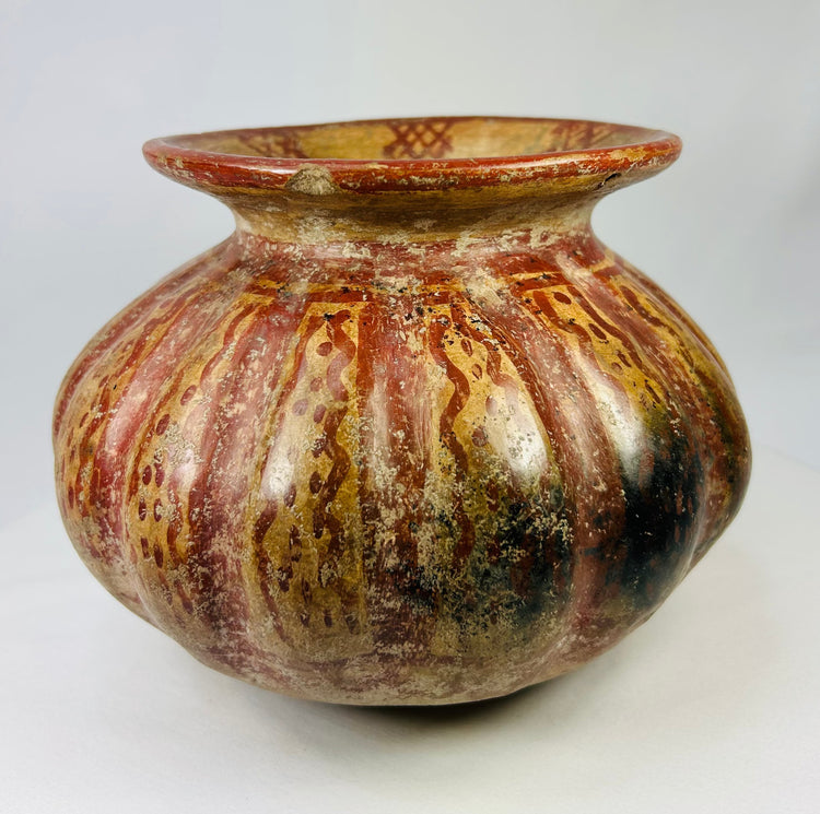 Side view of a Pre-Columbian Moche-style ceramic vessel showing red and gold streaked painted surface.