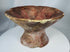Ancient footed ceramic vessel featuring radiating triangular decoration and extensive archaeological wear.