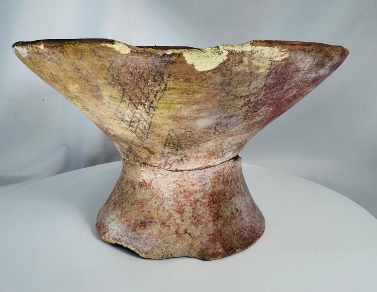 Ancient terracotta offering vessel displaying red and cream painted decoration and historic restorations.