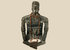 Front view of Pre-Columbian seated shamanic terracotta figure with red beads and headdress on a beige background.