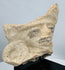 Ancient terracotta ceremonial fragment with fan-shaped crest, human visage, and remnants of dark pigment.