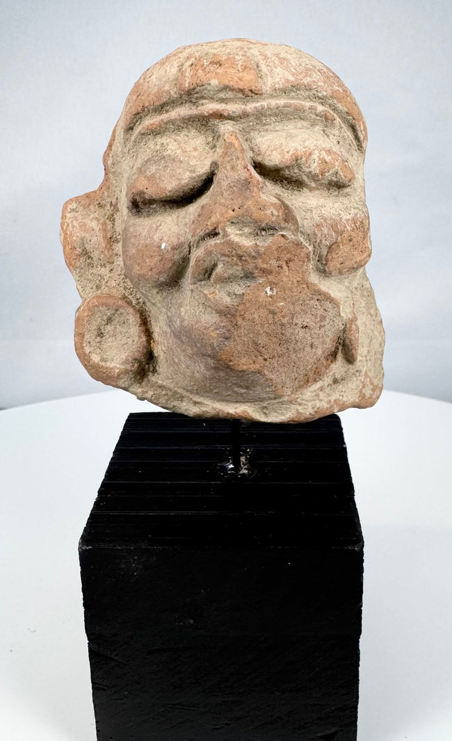 Pre-Columbian sculptural head fragment mounted on a modern display stand