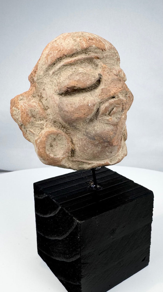 Ancient Mesoamerican figure head with deeply recessed eyes and circular ear ornaments