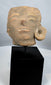 Ancient Mesoamerican ceramic head sculpture fragment with weathered surface and ear ornament.