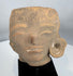 Ancient West Mexican ceramic head fragment depicting stylized facial features and preserved ear ornament.