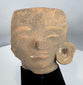 Ancient West Mexican ceramic head fragment depicting stylized facial features and preserved ear ornament.