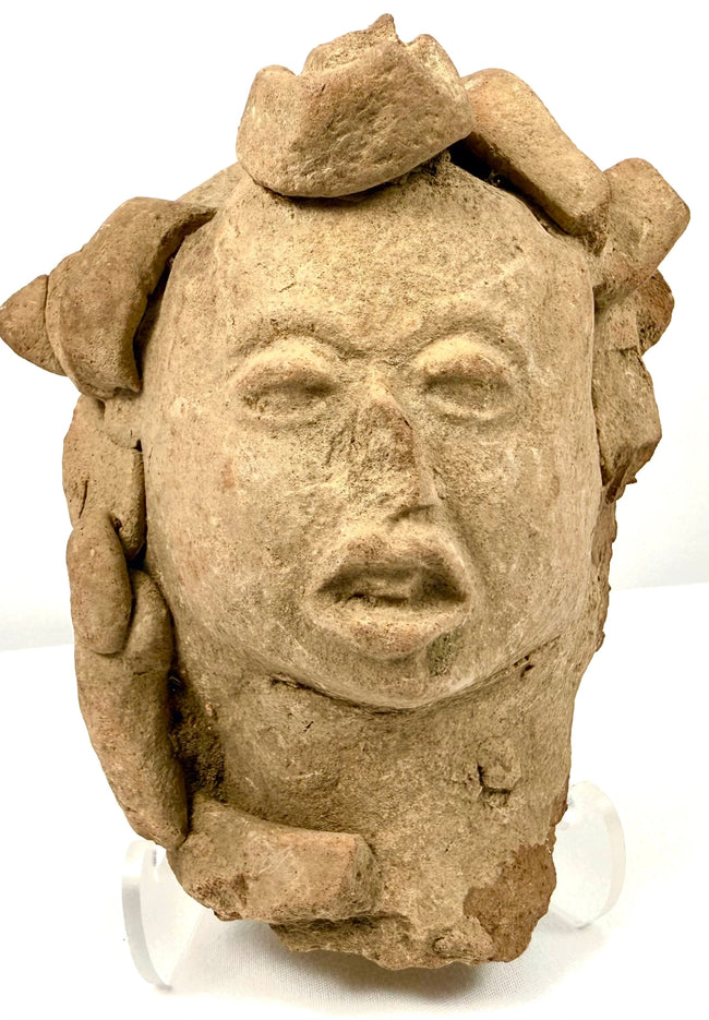 Frontal view of ancient Pre-Columbian terracotta head artifact with complex crown