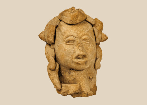 Ancient Pre-Columbian terracotta head from Mesoamerica, featuring stylized facial features with closed eyes, parted lips, and remnants of elaborate headdress elements, hand-molded from clay, dating between 1000–1500 CE, likely used as a ritual offering or funerary effigy.