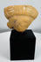 Terracotta human effigy head fragment mounted for display, retaining traces of original white pigment.