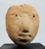 Ancient terracotta effigy head fragment displaying a prominent nose, recessed eyes, and pursed lips.