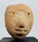 Ancient terracotta effigy head fragment displaying a prominent nose, recessed eyes, and pursed lips.