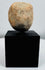 Stylized Pre-Columbian terracotta face fragment mounted for display with visible weathering and age.