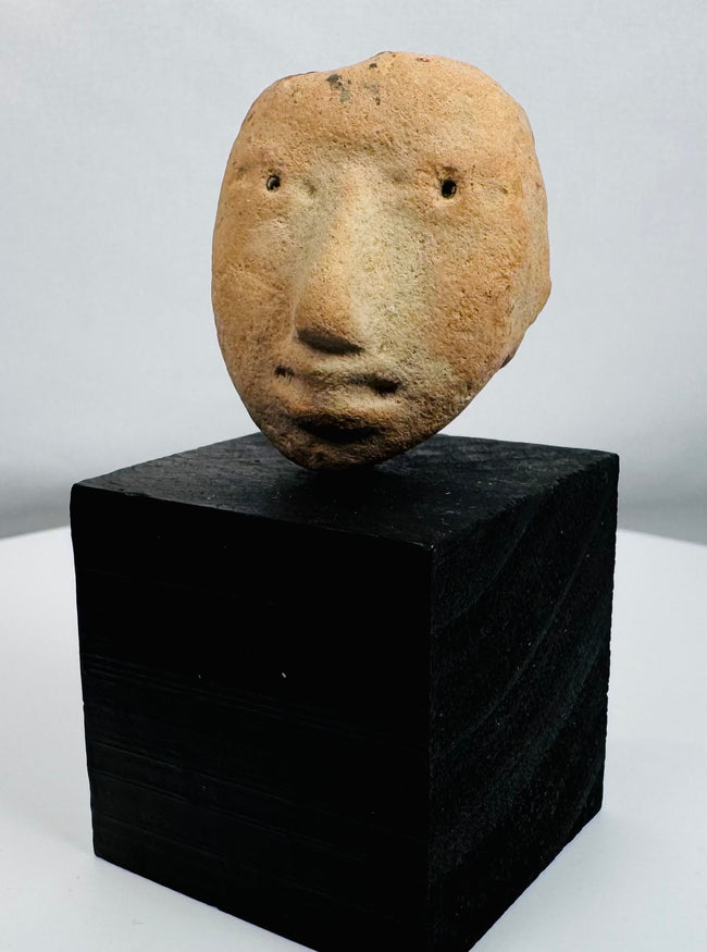 Pre-Columbian ceramic human head fragment from the ancient Americas with weathered archaeological surface.