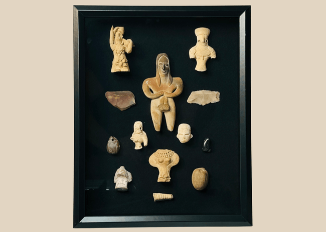 Framed collection of Pre-Columbian terracotta and stone artifacts displayed in a shadowbox.