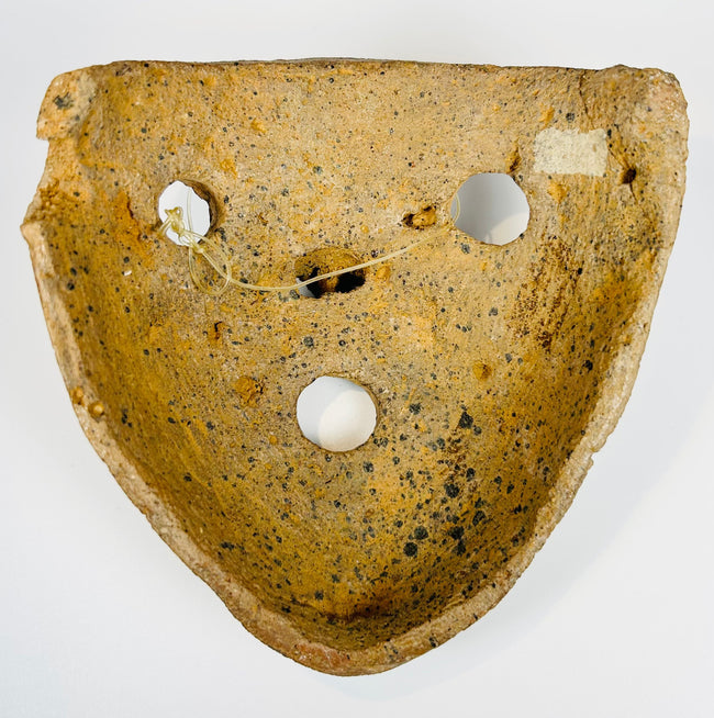 Mesoamerican clay mask with bold features and burial encrustation