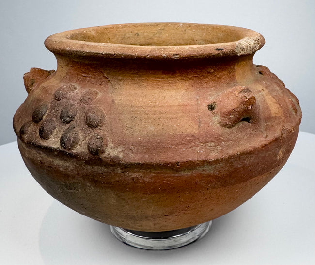 Pre-Columbian ceramic vessel featuring raised decorative elements and a naturally aged red-brown clay surface.