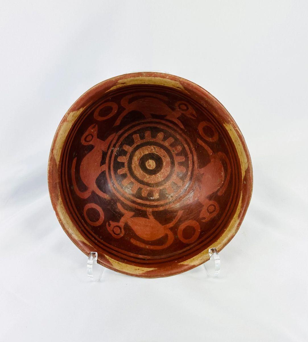 Terracotta Nariño culture bowl from Colombia and Ecuador, decorated with bichrome slip, negative resist geometric border, and four monkeys in the interior, dating from 800–1500 CE.