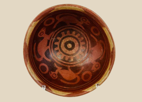 Terracotta Nariño culture bowl from Colombia and Ecuador, decorated with bichrome slip, negative resist geometric border, and four monkeys in the interior, dating from 800–1500 CE.