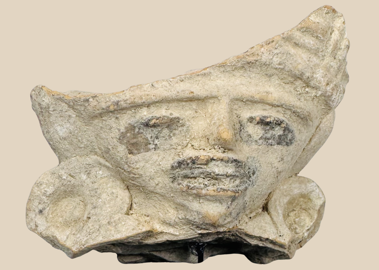 Pre-Columbian terracotta figural fragment depicting a stylized human face with large earspools and fan-shaped headdress, Mesoamerica, circa 600–1200 CE.