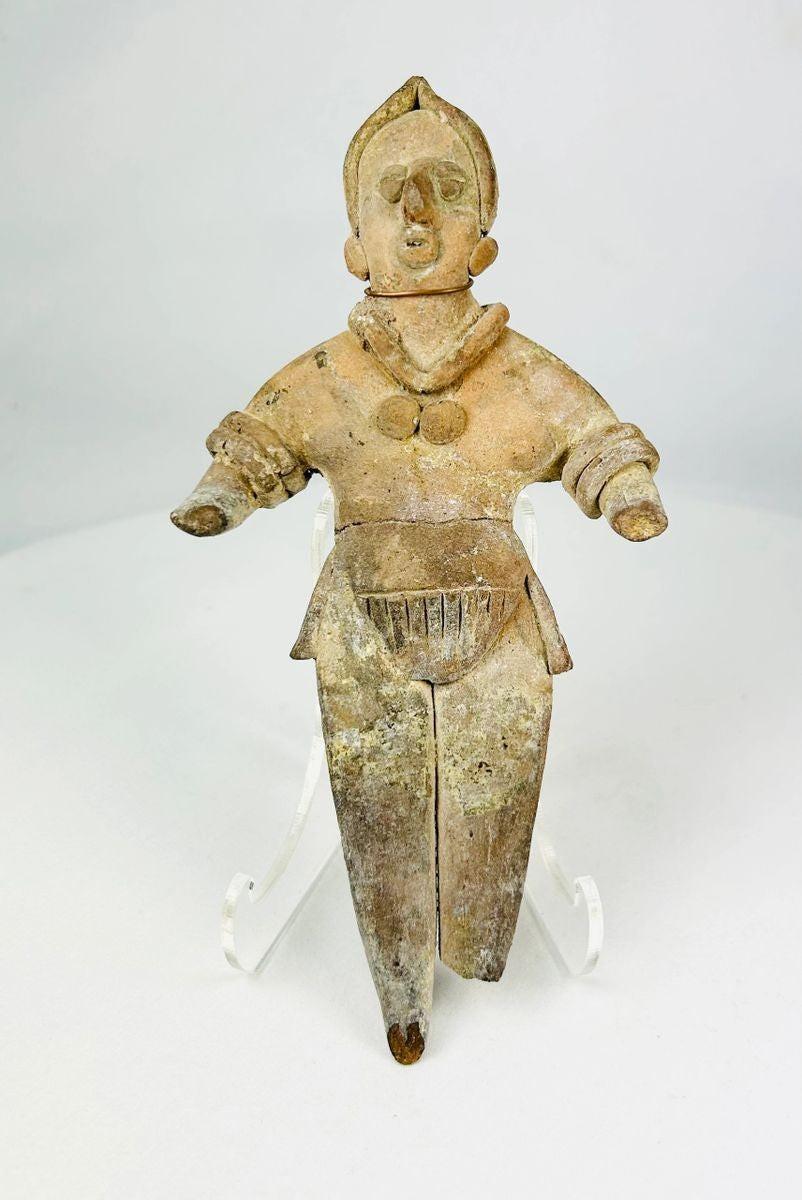 Ancient Pre-Columbian terracotta figurine, circa 300–900 CE, depicting a stylized human figure with detailed jewelry and headdress, shown standing with arms extended.