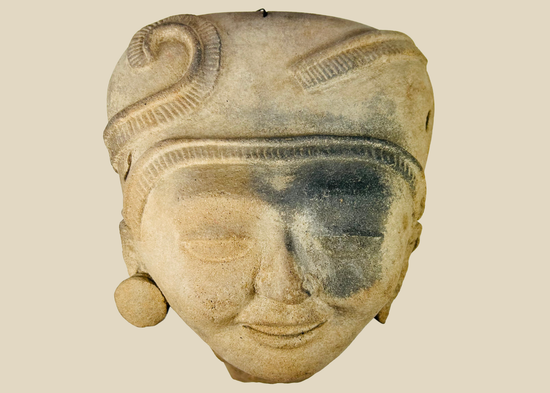 Pre-Columbian terracotta head with intricate hairstyle and large ear ornaments, Mesoamerican origin.