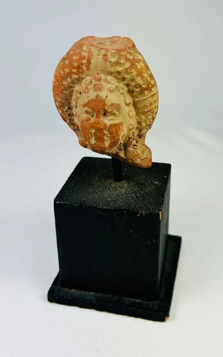 Pre-Columbian terracotta head fragment, circa 500–1200 CE, with serene facial features, ornate headdress, and traces of red and white pigment.