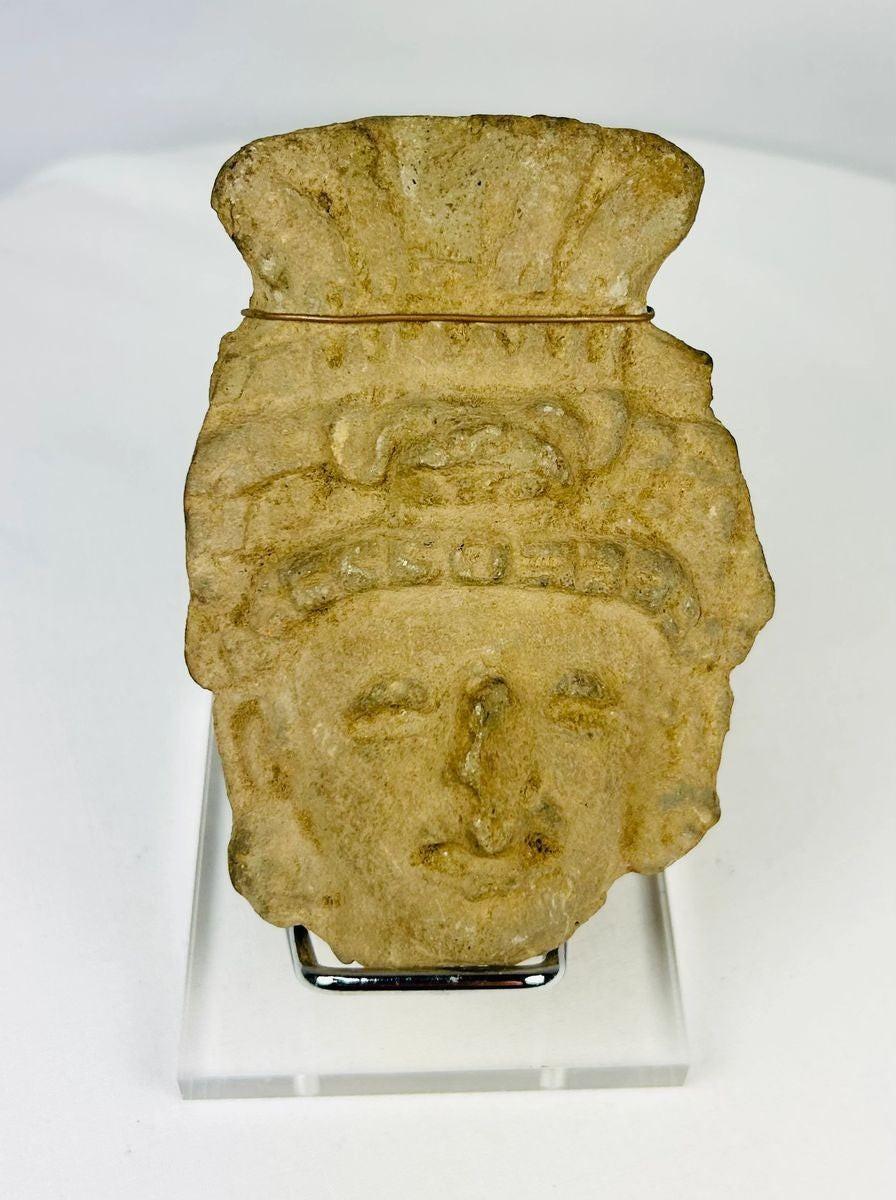 Pre-Columbian terracotta head fragment, circa 1st millennium CE, with stylized facial features and ornate fan-like headdress, weathered patina.