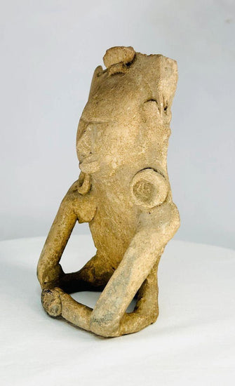 Ancient Mesoamerican terracotta figurine depicting a seated human with helmet-like headpiece, large circular ear ornaments, and hollow cavity in back for ritual use, Classic Period (200–800 AD).