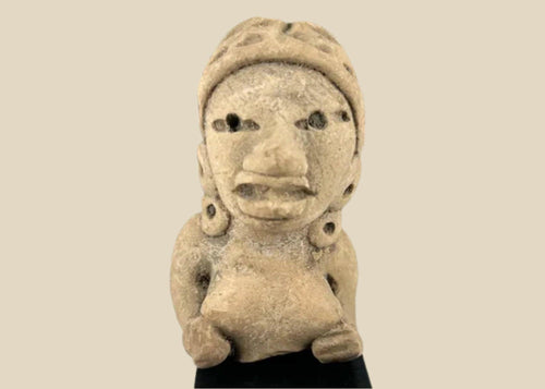Ancient West Mexican terracotta female figurine, seated with earspools and headdress, hand-modeled with expressive facial features, mounted on a black display base, photographed on a white background.