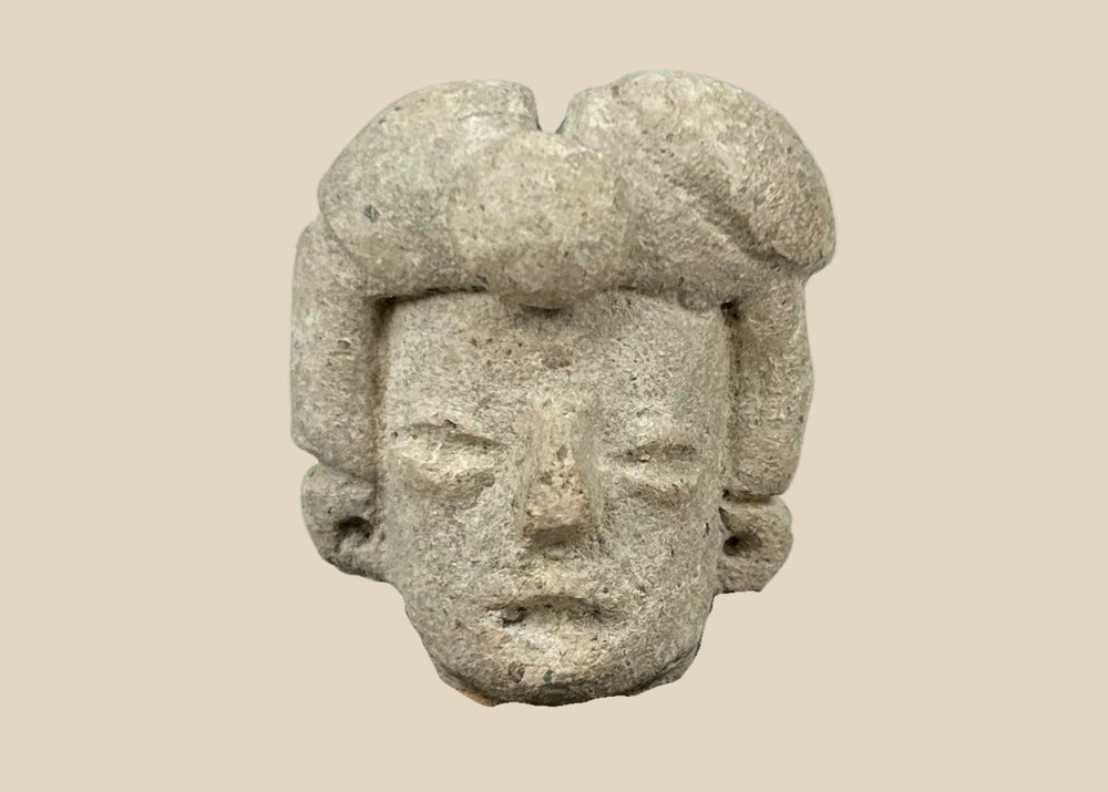 Ancient Pre-Columbian terracotta head fragment from West Mexico, Nayarit/Jalisco shaft-tomb culture, with almond-shaped eyes, straight nose, and stylized coiffure, mounted on a black display base, photographed on a white background.
