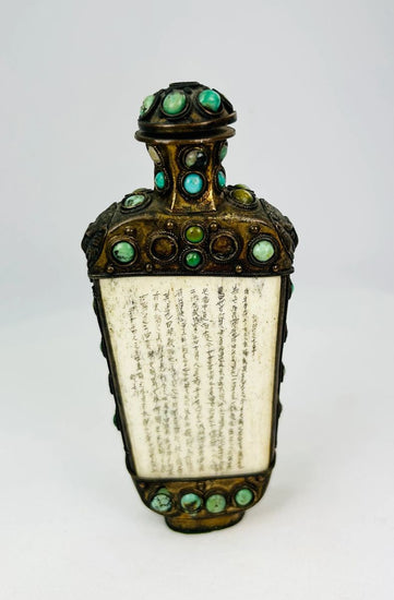 Ornate bronze ritual flask from the Sino-Tibetan border region, decorated with cabochon turquoise and green stones, carved bone panels with Tibetan or Sanskrit inscriptions, and guardian lion masks in relief, 5 inches tall by 2.5 inches wide, late Qing Dynasty, circa late 19th century.