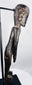 Side view of elongated moai kavakava-inspired wooden sculpture on black display stand