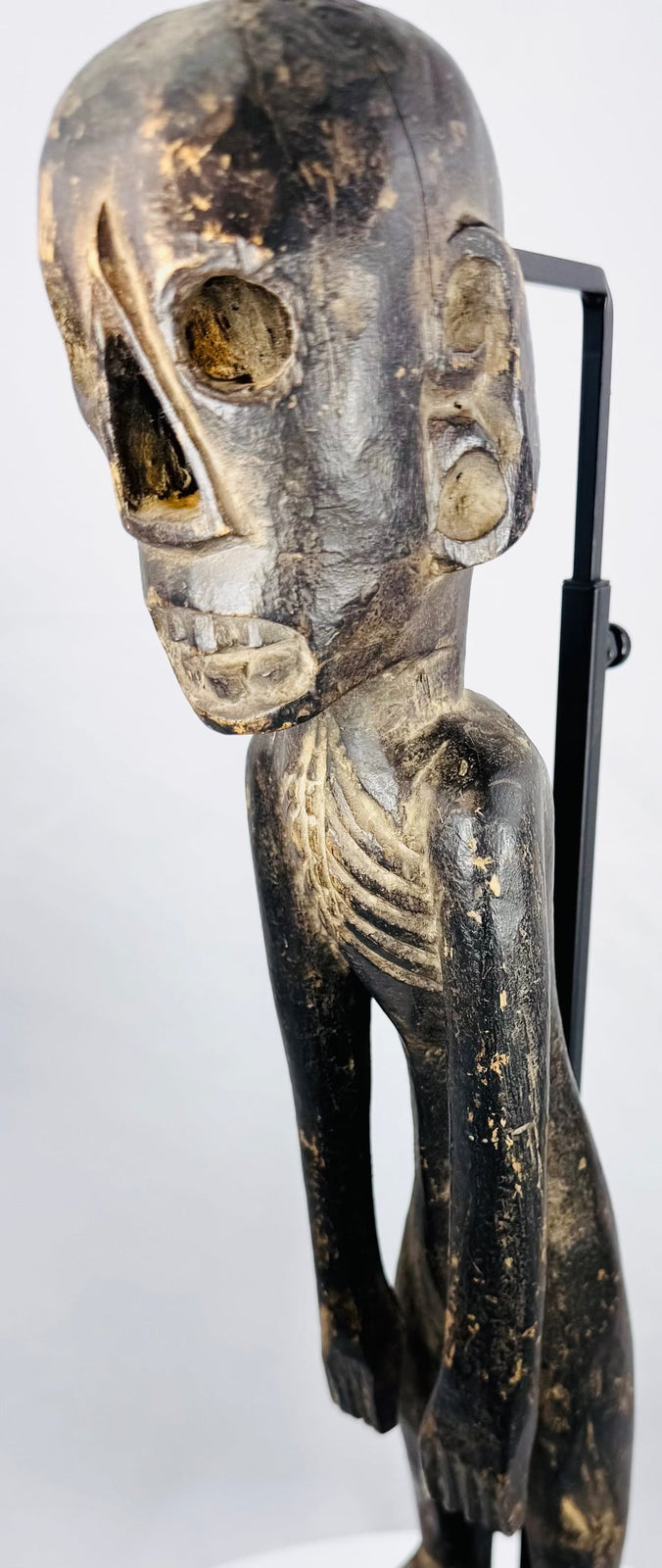 Antique Polynesian-inspired wooden figure with elongated limbs and weathered dark finish