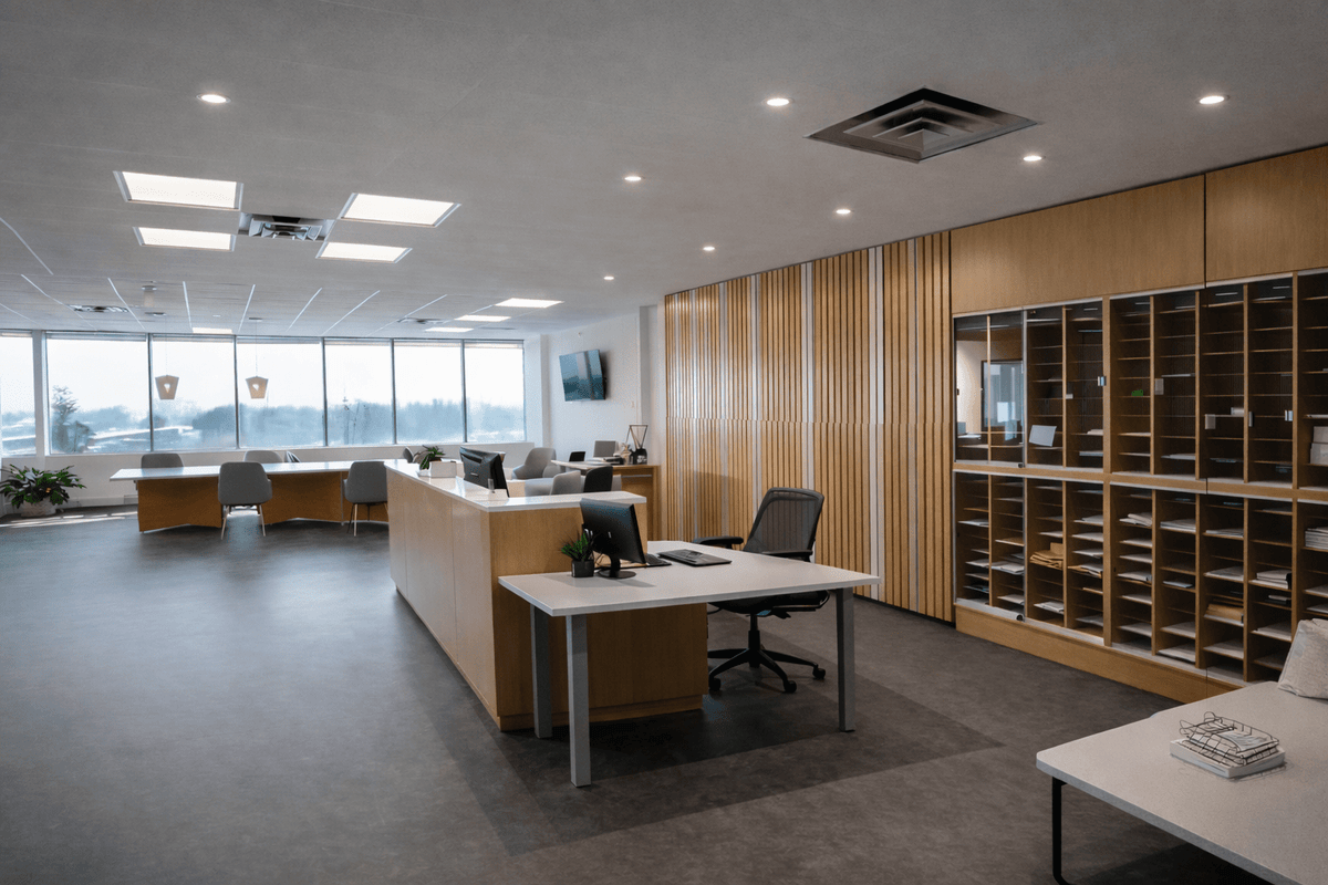 Modern reception and gallery office interior with wood panel walls, desk workspace, mail cubbies, and large windows with natural light. The Relic and Rarity lobby. 