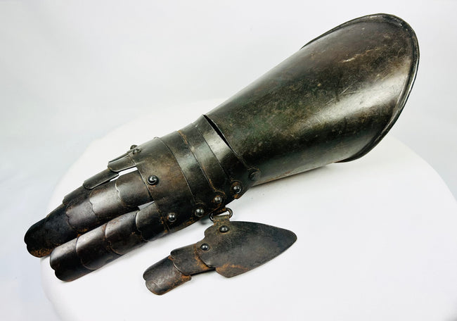 Steel battlefield-style gauntlet with overlapping finger plates and flared cuff, museum-quality photograph.