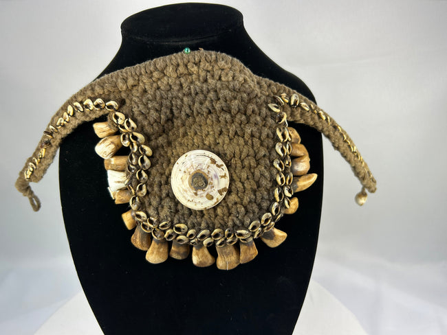 Melanesian ritual adornment featuring cowrie shell and pierced animal teeth