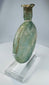 Authentic Roman Empire glass flask featuring flattened circular form and mineral deposits