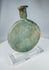 Ancient Roman translucent green glass vessel with weathered surface and elongated neck