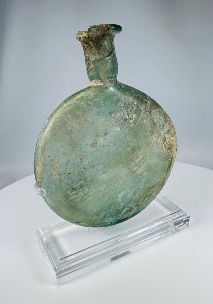 Ancient Roman translucent green glass vessel with weathered surface and elongated neck