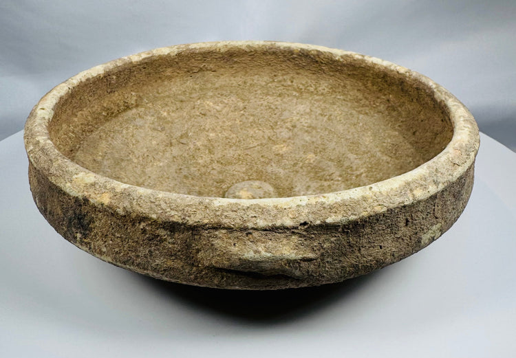 Interior view of an ancient Roman terracotta bowl highlighting the raised central boss and surviving white slip.