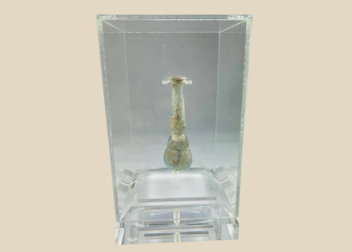 Ancient Roman pale turquoise blown glass balsamarium, 2nd–3rd Century CE. Double-gourd body with tapering neck and outfolded lip, featuring natural iridescent patina. Hand-blown vessel used for perfumes, ointments, and luxury grooming, reflecting Roman craftsmanship, refinement, and elite culture.