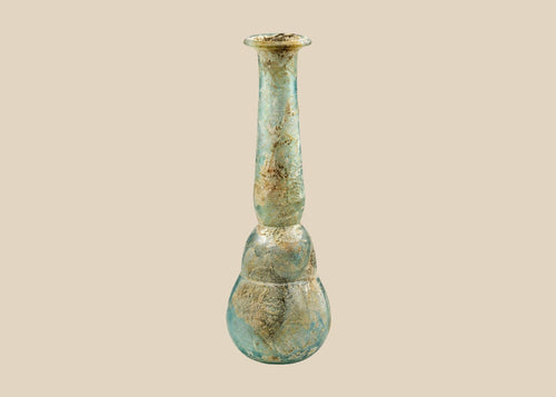 Ancient Roman iridescent turquoise glass vessel with brown weathering on beige background
