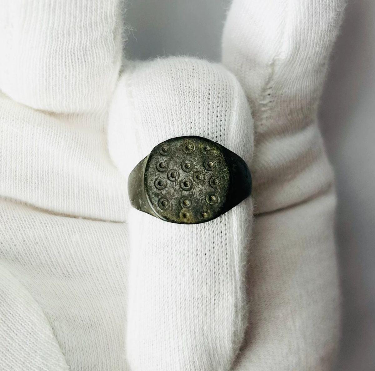 Ancient Roman bronze ring, size 7 US, featuring a flat bezel engraved with irregular “ring and dot” motifs symbolizing the sun, with authentic patina and well-preserved surface from the 1st–3rd century CE.