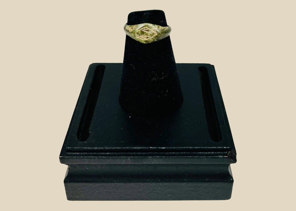 Authentic Roman bronze signet ring, circa 100–300 CE, with oval bezel engraved with geometric intaglio diamond motif, slender tapered band, and rich green patina from centuries of burial, used for sealing documents and personal identity.